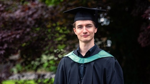 Jevon Mckenna yn ei gap a’i ŵn academaidd.