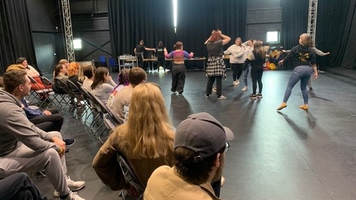 Grŵp o bobl yn gwylio perfformiad gan aelodau Theatr fel Arfer Cynhwysol