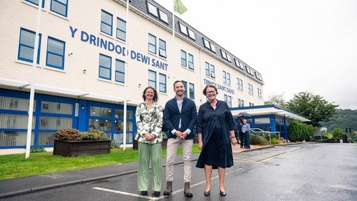 Kelly Williams, Owen Derbyshire a’r Athro Elwen Evans yn sefyll yn gwenu y tu allan i Adeilad Dewi.