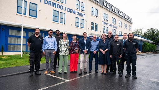 Yr Athro Elwen Evans, Owen Derbyshire a chynrychiolwyr y tîm Ystadau yn gwenu y tu allan i Adeilad Dewi ar Gampws Caerfyrddin.