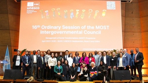 Attendees of the 16th Ordinary Session of the UNESCO - MOST Intergovernmental Council posing together on stage for a cheerful group picture.