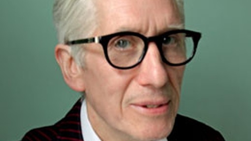 John Wood yn edrych ychydig i'r ochr tuag at y camera trwy sbectol rhimyn trwchus ar ddull y chwedegau; mae ei wallt gwyn wedi ei frwsio yn ôl o'i wyneb ac mae'n gwisgo siwt siaced resog.