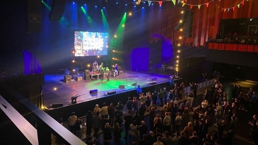 Inside Swansea Arena with a band on the stage and the audience up and dancing.