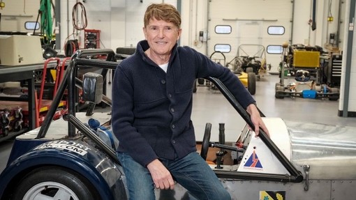 Nick Fry is pictured in the University's IQ building sitting on a motor vehicle which is being worked on.