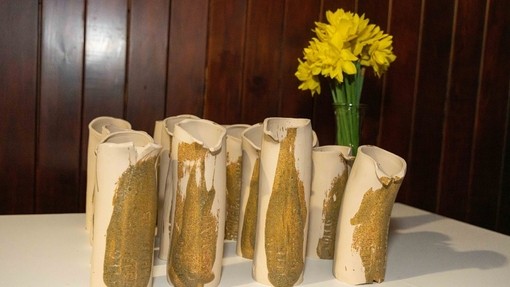 A photo of the Awards - ceramic cream and golden jugs placed on a table with daffodils in the foreground