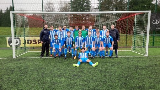 The UWTSD football team stand in their kit taking a team photo inside the goal