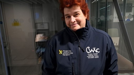 Dr Liz Walder standing in front of a glass door.