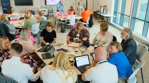 A cohort of the Professional Practice Framework sitting around a table at a conference/ lecture