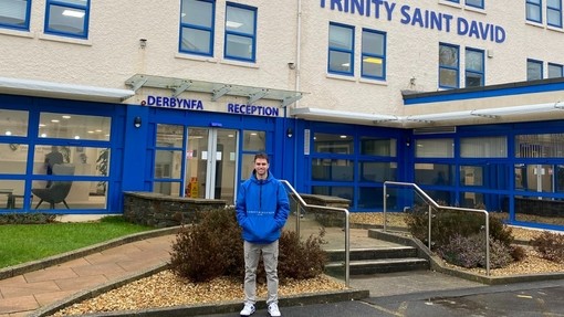 A picture of James Piggott standing outside the Dewi Building on the Carmarthen Campus