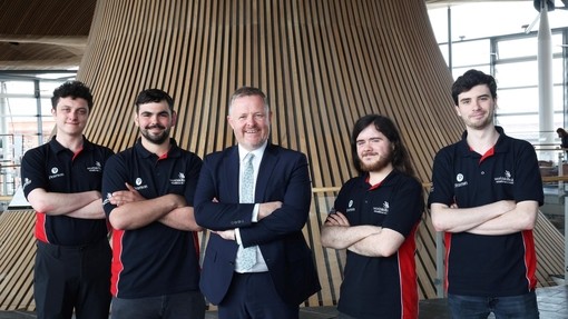 A smiling group pic, arms folded, standing inside the Senedd.