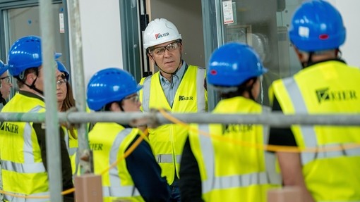 A group in protective clothing viewing the new building.