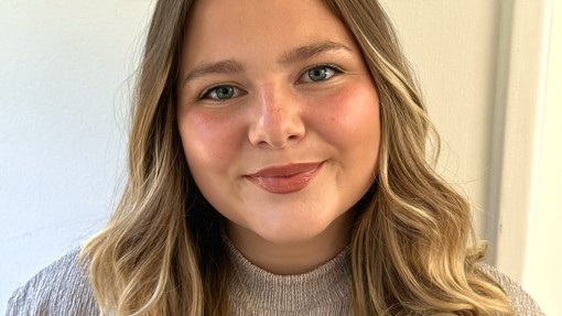 A happy smiling student wearing a grey top.