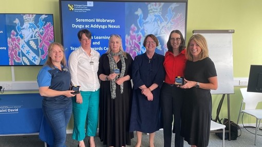 Group photo of the Nexus awards 2024 winners on the Carmarthen campus staning in front of a screen in a teaching room