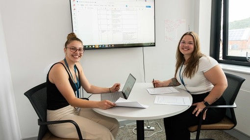 Smiling students sitting at a desk in the Psychology lab