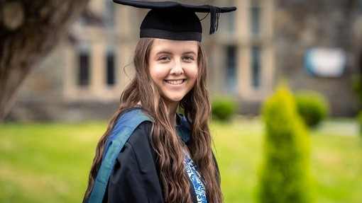 Headshot of Cerys Bailey in graduation gown on Carmarthen campus
