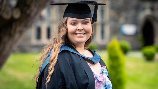 Ellie Hones headshot in graduation gown on Carmarthen campus