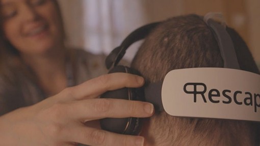 Woman placing a VR headset on another person.