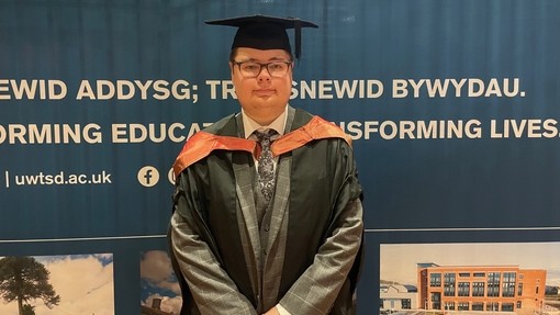 A proud and smiling graduate wearing his cap and gown.
