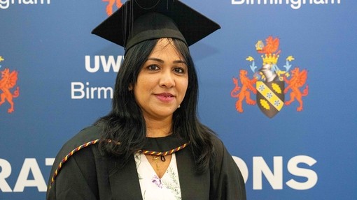 A proud and smiling graduate wearing her cap and gown.