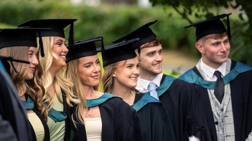 A group of happy, smiling and proud graduates dressed in their cap and gowns.