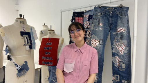 A smiling surface pattern and design graduate standing in front of colourful work.