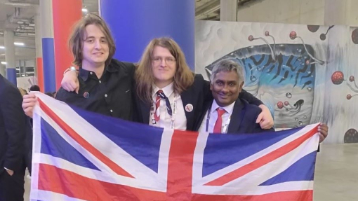 Three people celebrating holding a red, white and blue flag.