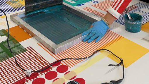 Colourful prints being worked by a person wearing gloves.