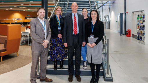 Five people standing on the steps in the foyer of the University's IQ Building in Swansea.