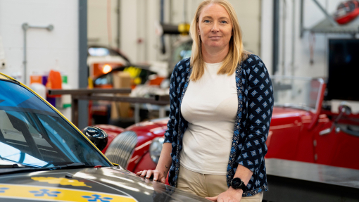 A senior lecturer standing in front of a race car in the university workshop.