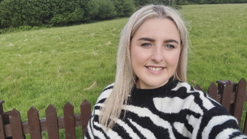 Menyw yn cymryd hun-lun gyda gwyrddni yn y cefndir
