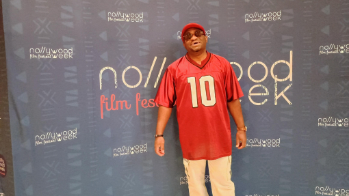Tunji Offeyi in red top in front of Nollywood popup stand