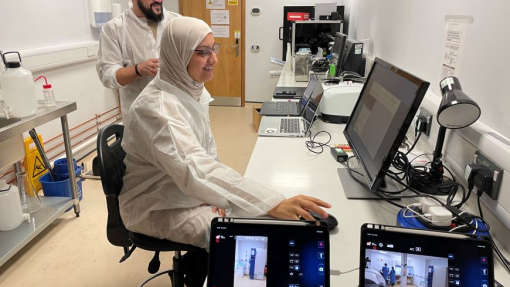 A man and woman working in a lab environment surrounded by computer screens.
