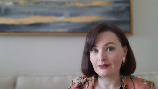 Headshot of Krystyna Cap with painting in the background