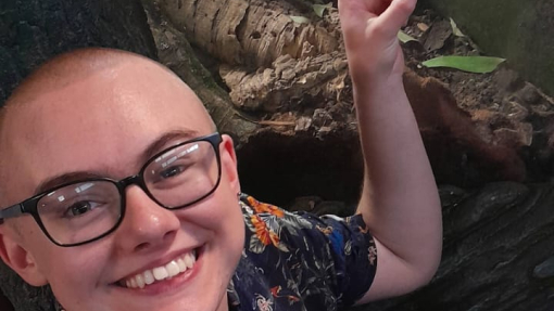 A smiling, happy student pointing to an exhibit at an event.