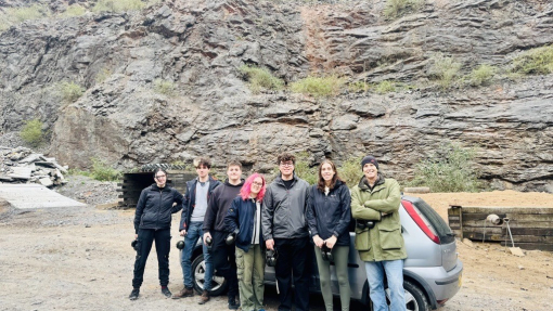 A group of students and a lecturer standing in a disused quarry.