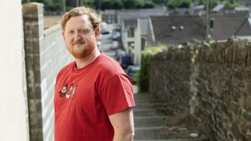 Man standing outside smiling in red t-shirt
