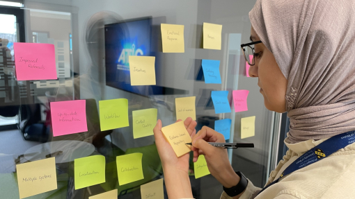 A researcher with coloured post it notes on a computer background.