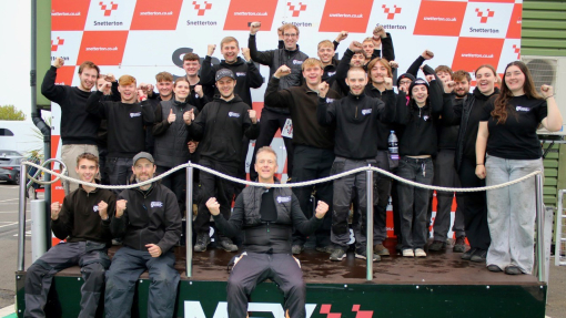 A large group of students and lecturers celebrating on the race podium.