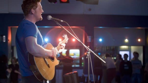 Man singing to a crowd on a guitar