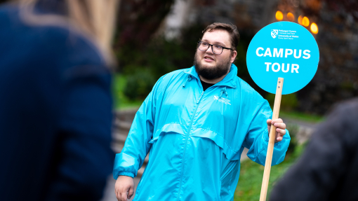 student ambassador holding follow me sign on tour