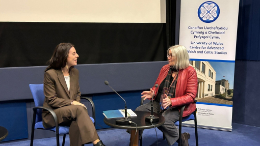Dr Jaione Diaz Mazquiaran and Professor Elin Haf Gruffydd Jones sitting and in discussion with a CAWCS banner in the background