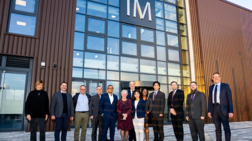 A group of people standing in a curved line in front of a glass-fronted building.