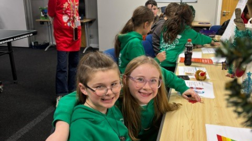 Two excited and happy children learning about Psychology at a Christmas showcase with writing materials and crafts on the table.