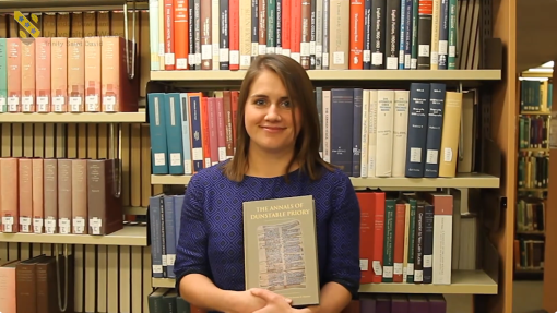 Dr Harriett Webster with her book in front of book shelf