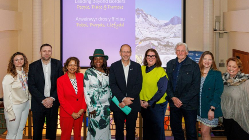 A group of people standing in a line in front of a large screen.