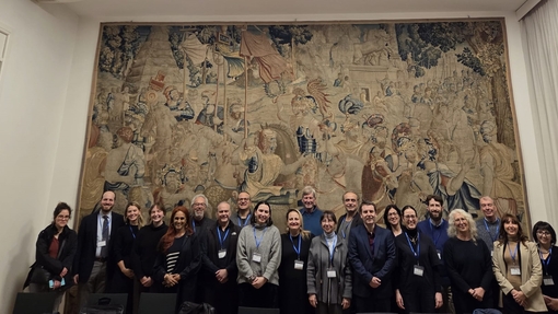 Group photo of those who took part in the conference with a very big Italian art work in the background
