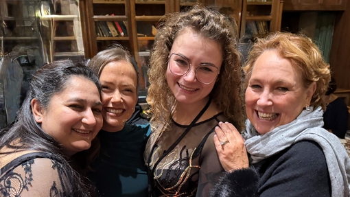A group of four happy, smiling women at a black tie event