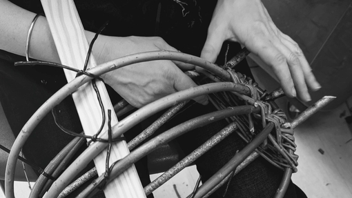 A mono images of two hands weaving.