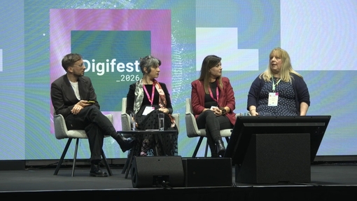 Laura Hutchings on stage at Digisfest sitting down as  panellist with three other individual