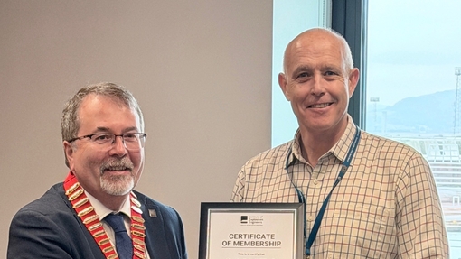 Two men shaking hands and one is holding a framed certificate.